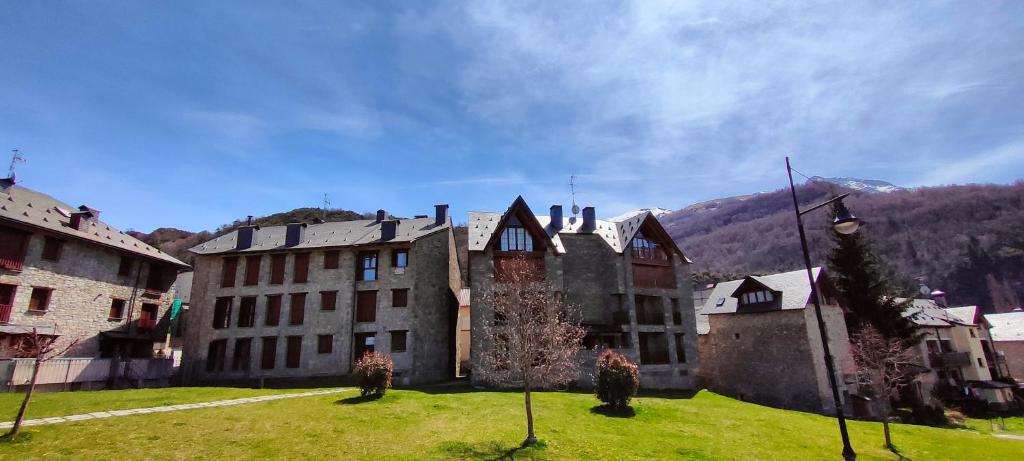 un antiguo edificio en un campo de hierba con montañas en el fondo en Los Cachorros, en El Pueyo de Jaca