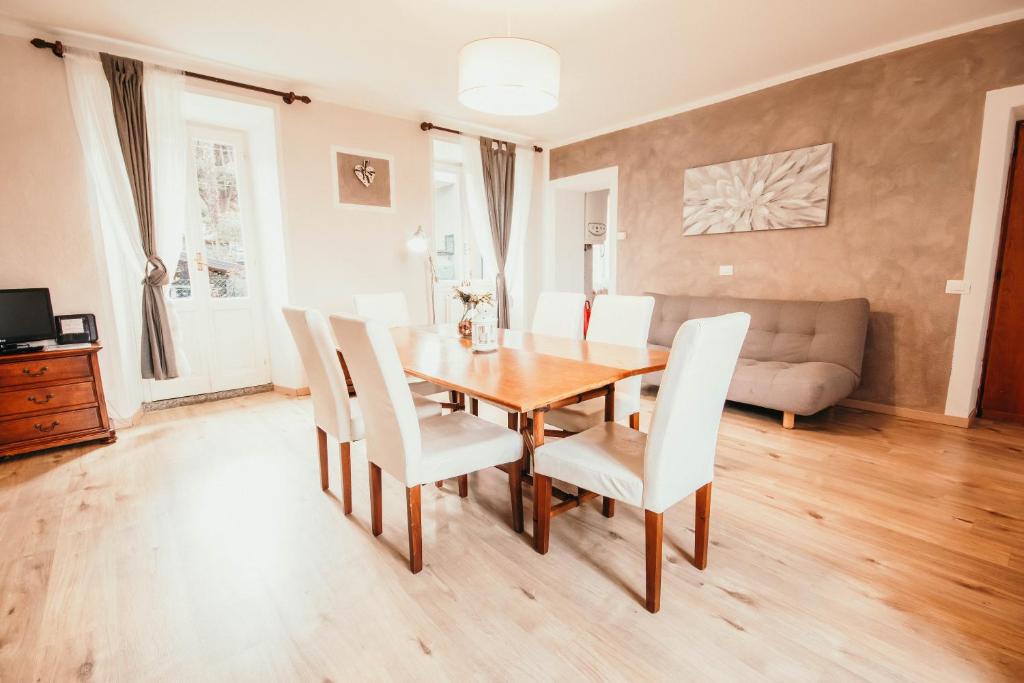 een eetkamer met een houten tafel en witte stoelen bij Appartamento Monna Lisa - Lakeside Leisure & Business in Stresa
