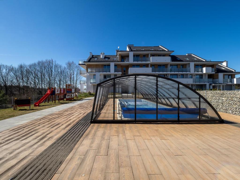 a glass bridge over a playground in front of a building at Apartament Baltic Sunrise in Sztutowo