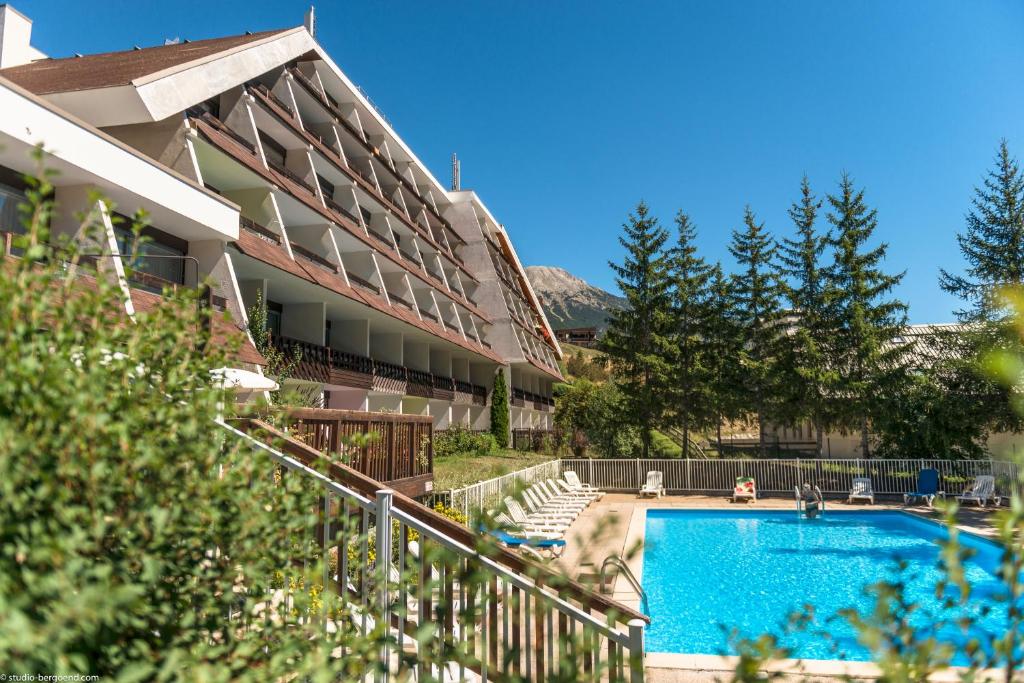 a hotel with a swimming pool in front of a building at Pierre et Vacances Serre Chevalier Chantemerle in Saint-Chaffrey