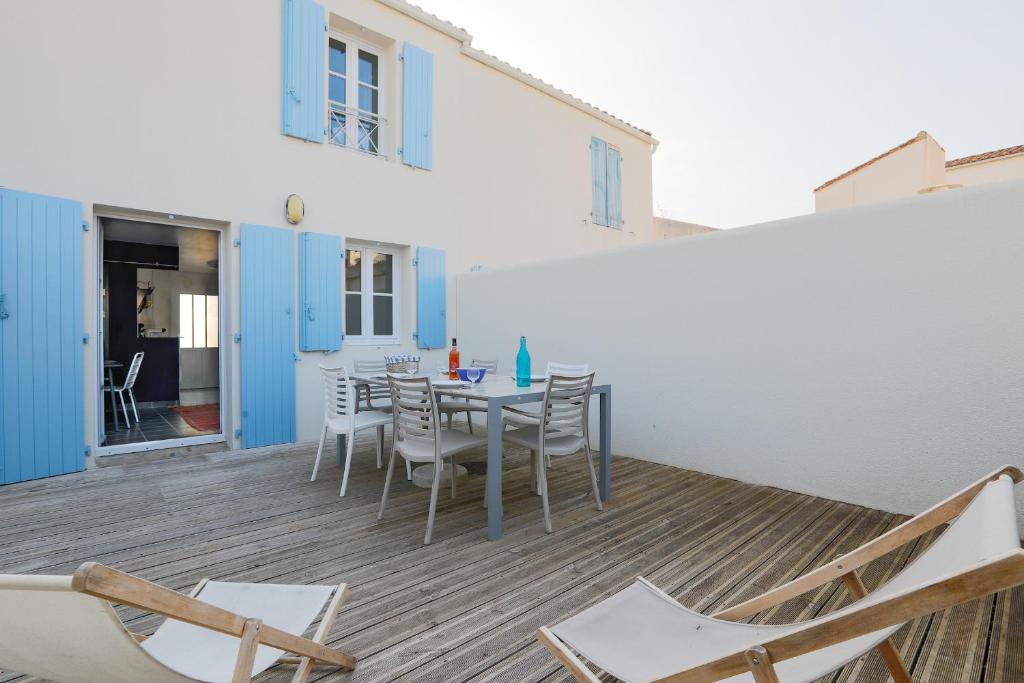 een kamer met een tafel en stoelen op een terras bij Jolie maison en residence - paradis des familles - Re Liberte in La Flotte