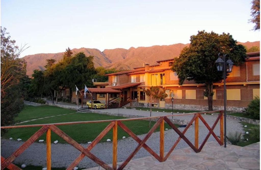 una valla frente a un edificio con montañas en el fondo en Hotel El Hornero Spa en Merlo