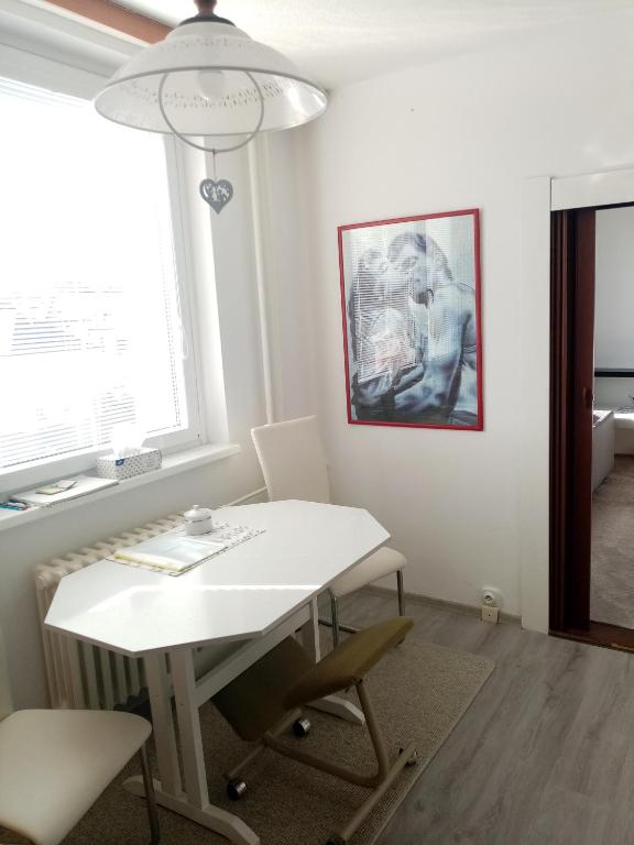 Biały stół i krzesła w pokoju z oknem w obiekcie Apartmán BlueA w Igławie