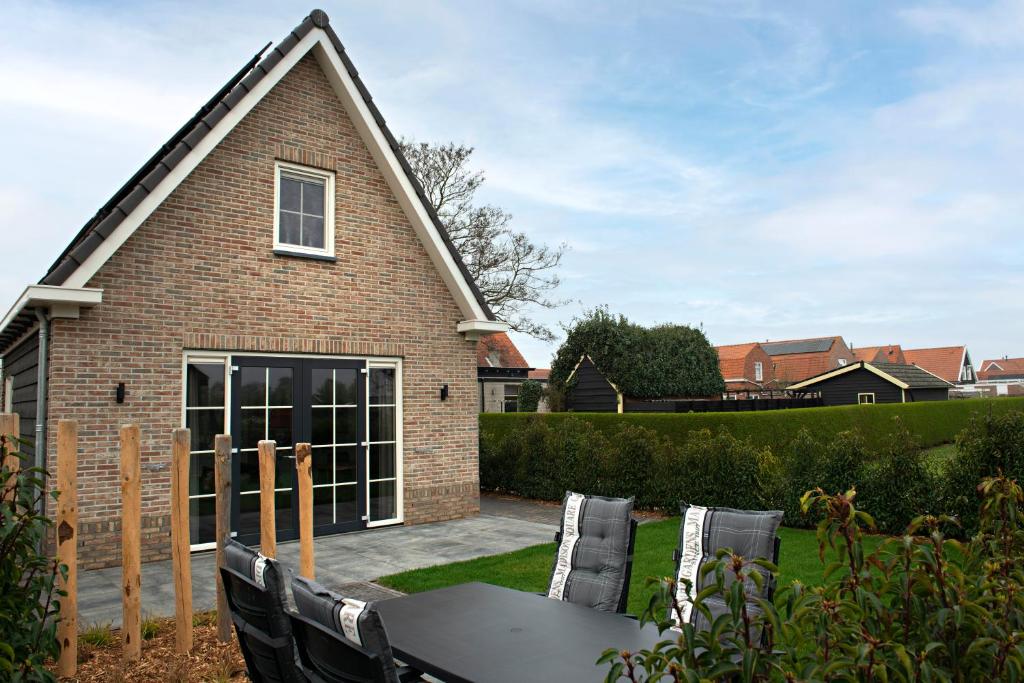 uma casa com uma mesa e cadeiras em frente em 't sfeeruus em Serooskerke