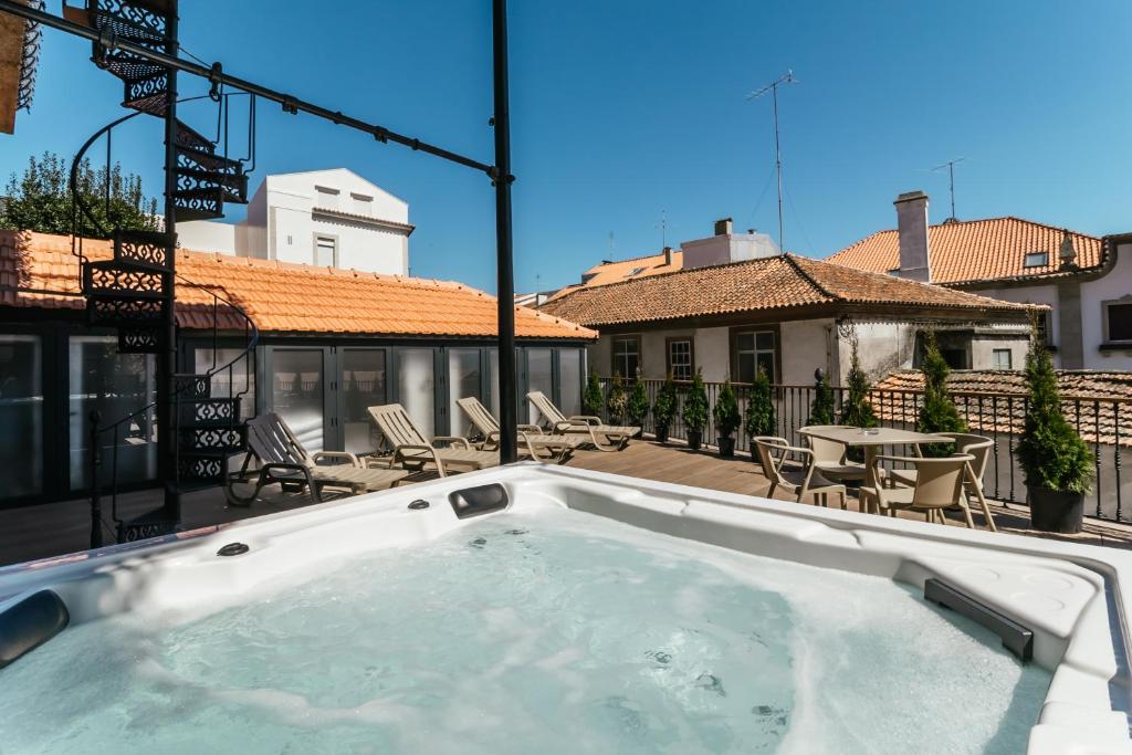 a hot tub on a balcony with chairs and a table at Royal Collection Covilhã in Covilhã