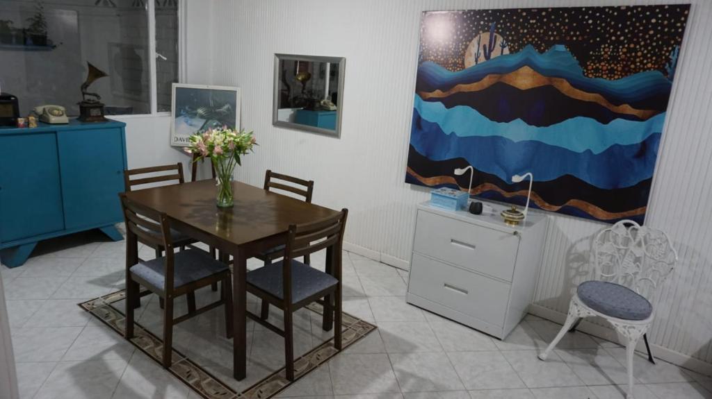 a dining room with a table and chairs and a vase of flowers at Habitaciones cerca del aeropuerto in Bogotá