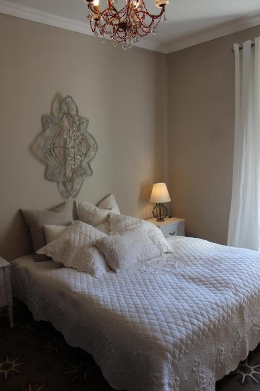 a bedroom with a bed with white sheets and a chandelier at Les Romarins B&B, 10 min d'Uzès, piscine et grand jardin, Table d'hôte in Uzès
