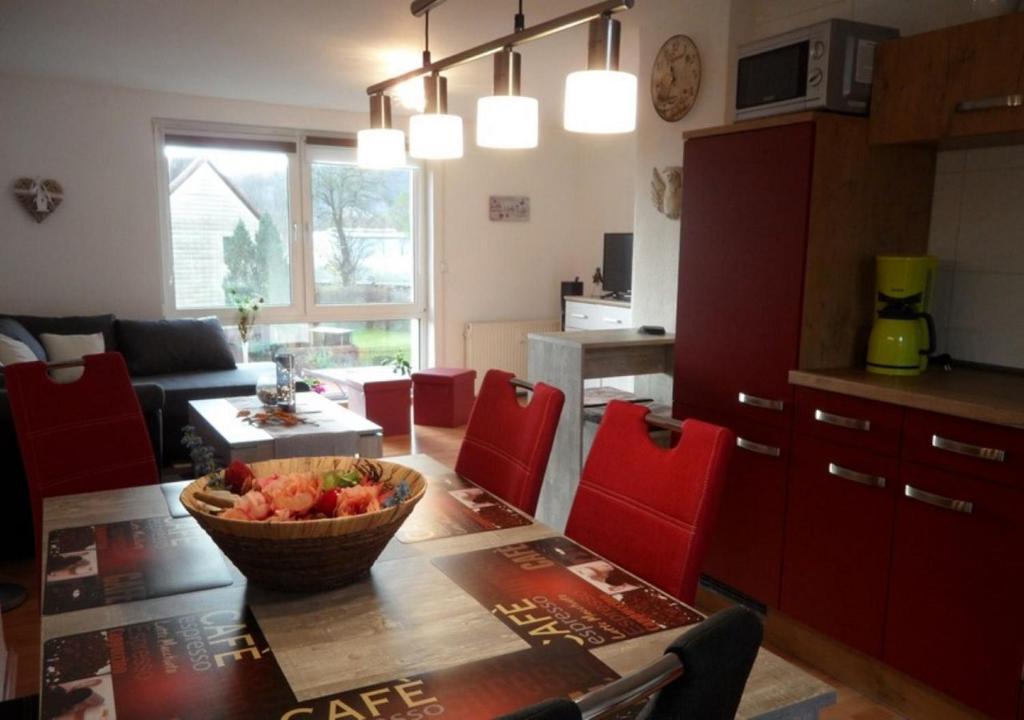 eine Küche und ein Wohnzimmer mit einem Tisch und roten Stühlen in der Unterkunft Haus Maisonette am Harz in Niedersachswerfen