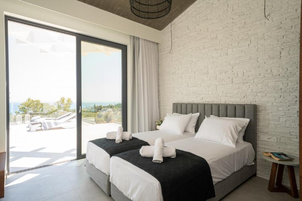 dwa łóżka w sypialni z dużym oknem w obiekcie White Blossoms Villas w mieście Trapezaki
