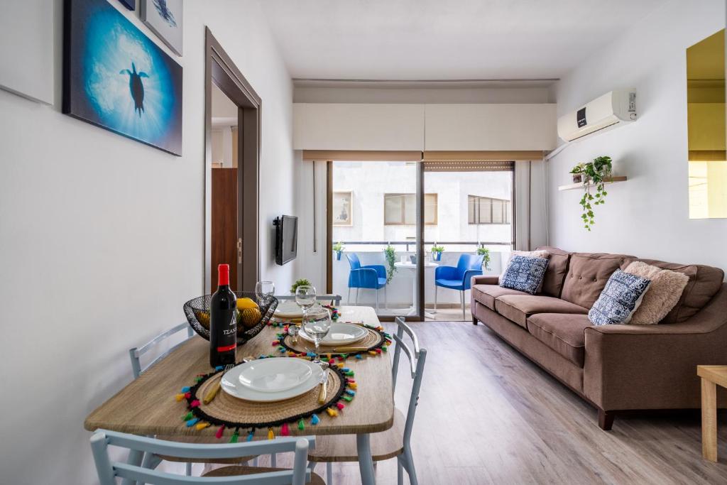 uma sala de estar com uma mesa e um sofá em Eleni’s 1-BR Apt in Larnaca Center em Lárnaca