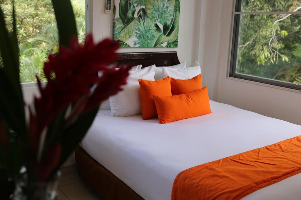 sypialnia z łóżkiem z pomarańczowymi i białymi poduszkami w obiekcie Albrook Inn w Panamie