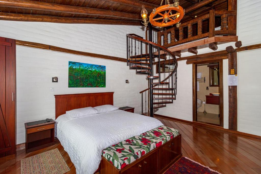 a bedroom with a bed and a spiral staircase at Hostal ILÉ in Baños
