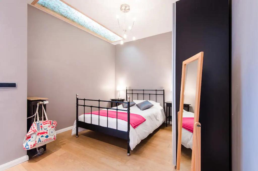 a bedroom with a bed with pink sheets and a mirror at VIEUX LILLE Porte de Gand Bienvenue chez NESTYOU, Lille in Lille