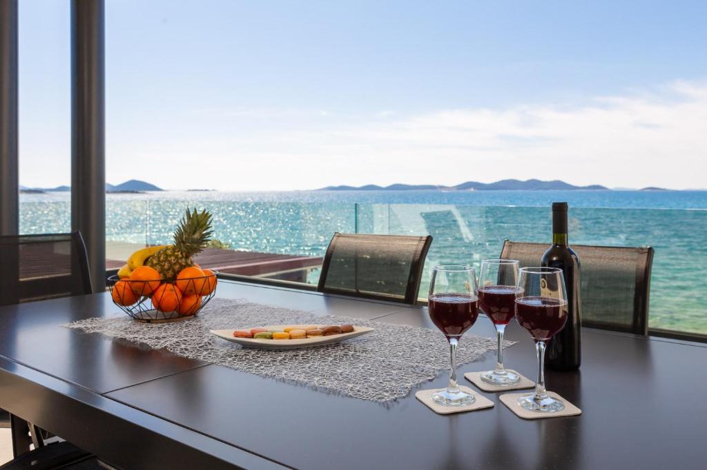 a table with two glasses of wine and a bowl of fruit at Luxury Apartment Blue Sky in Pakoštane