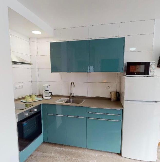 a kitchen with blue cabinets and a white refrigerator at Apartamentos Eldorado in Lloret de Mar