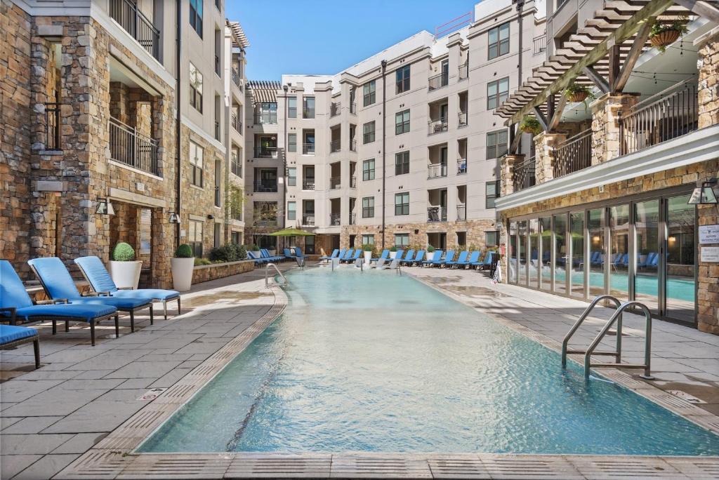 a swimming pool with blue chairs and buildings at Kasa Dilworth Charlotte in Charlotte