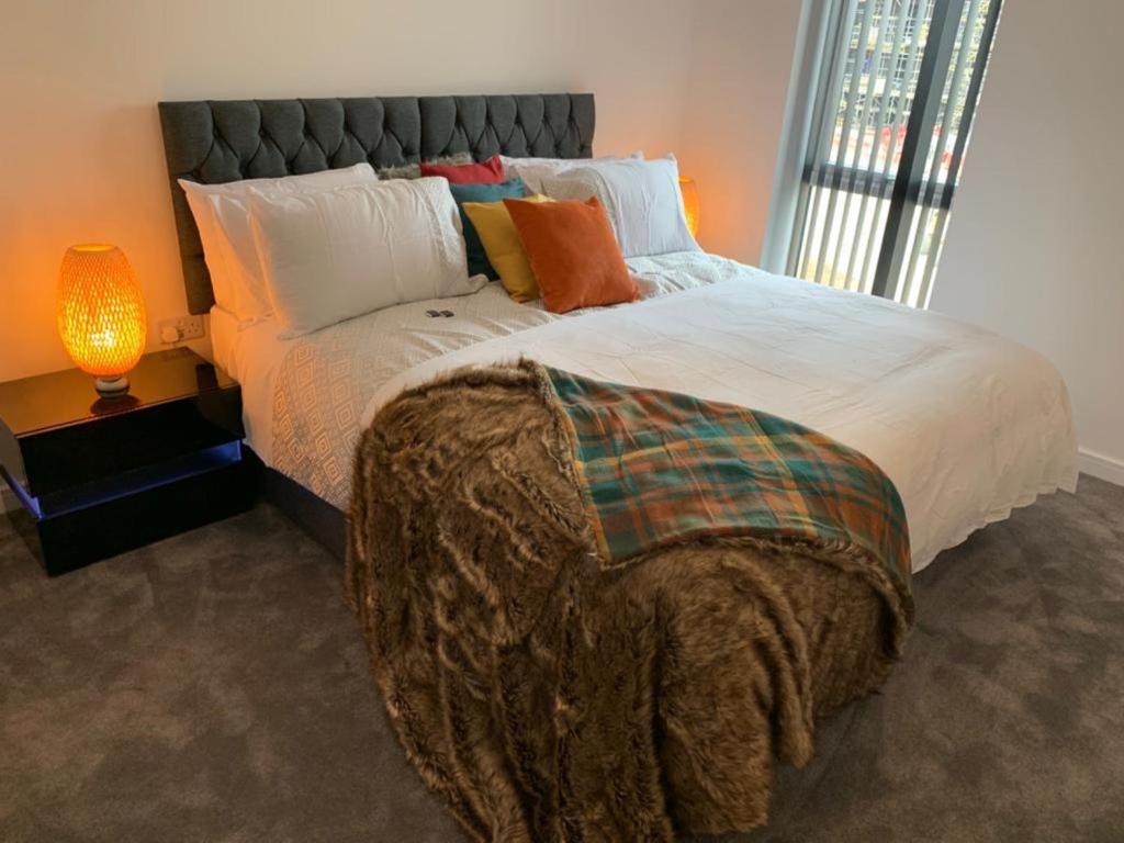een slaapkamer met een groot bed en een lamp bij Lakeside 2 BED LUXURY APARTMENT No PARTIES No EVENTS Early Check-in Late Check- Out Allowed in West Thurrock