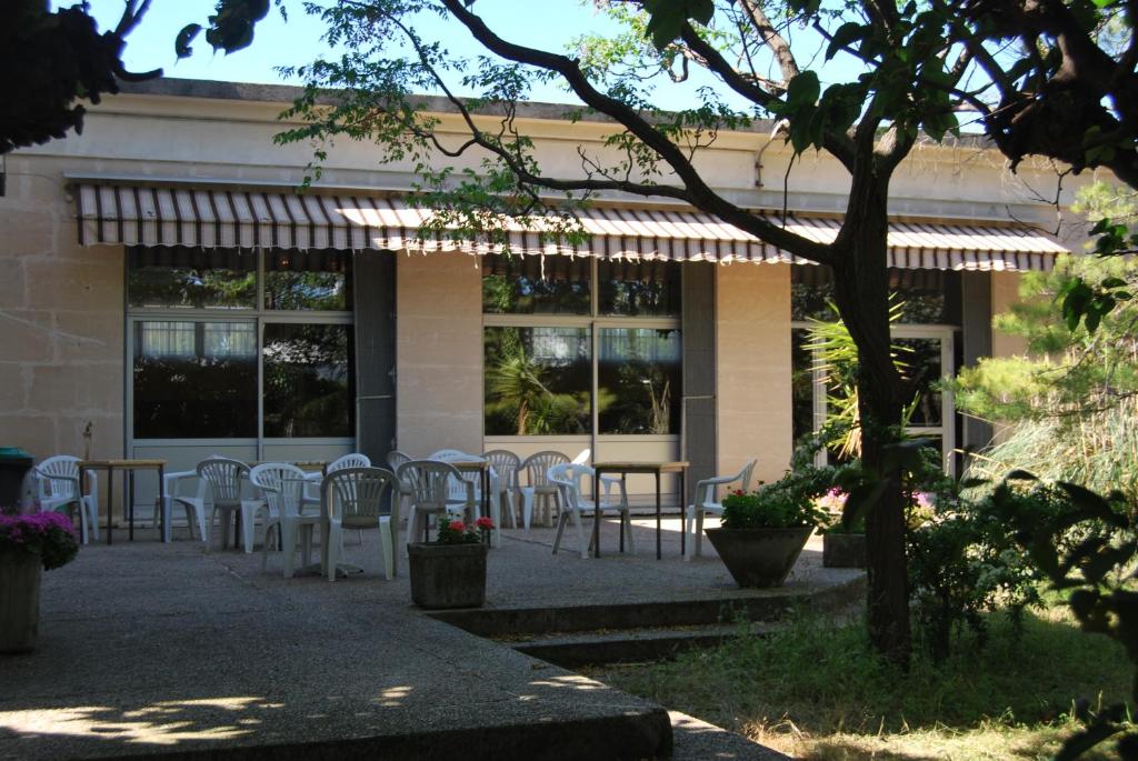 a patio with white chairs and tables in front of a building at Auberge de Jeunesse HI Arles in Arles