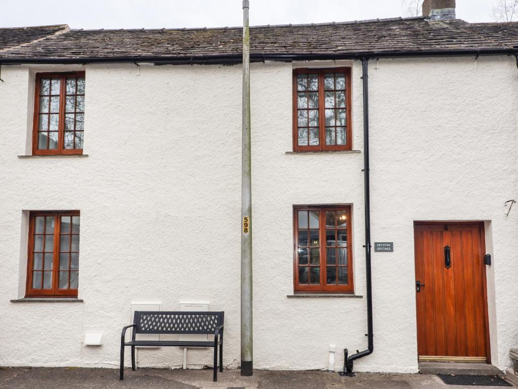 a white house with a bench in front of it at Fryston Cottage in Keswick