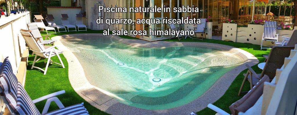 a swimming pool in the middle of a yard with chairs at Hotel Gioiosa in Cesenatico
