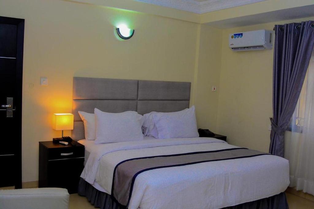 um quarto com uma cama grande com lençóis brancos e almofadas em TD RESIDENCE INN em Ijebu Ode