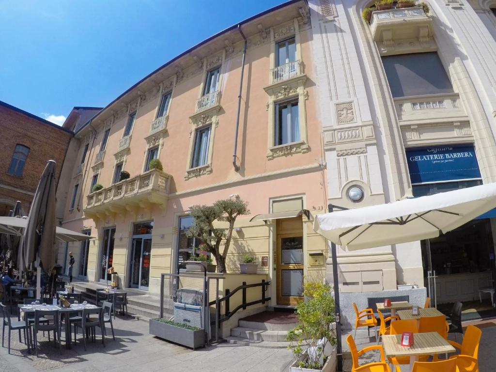 ein Gebäude mit Tischen, Stühlen und einem Regenschirm in der Unterkunft Locanda San Paolo in Monza