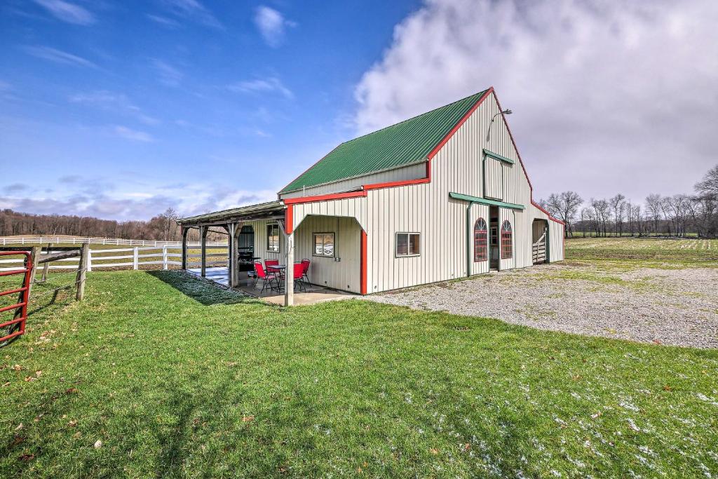 un grande fienile bianco con un tetto verde su un campo di Renovated Bunkhouse on 12-Acre Horse Farm! 
