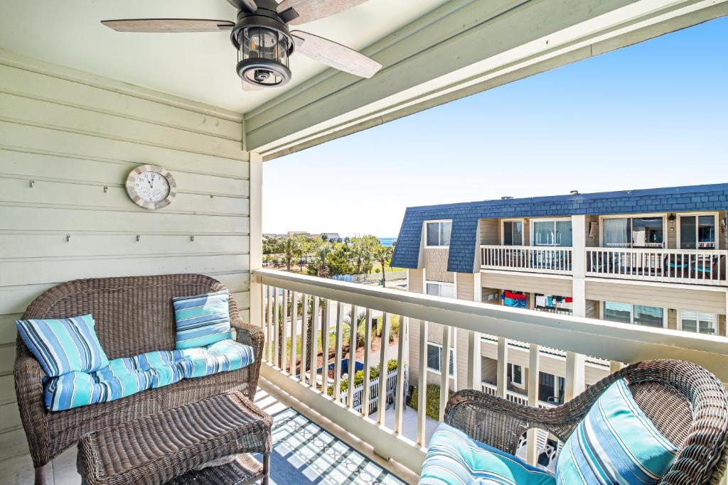 a balcony with two wicker chairs and a ceiling fan at Oceanside 306-B in Isle of Palms