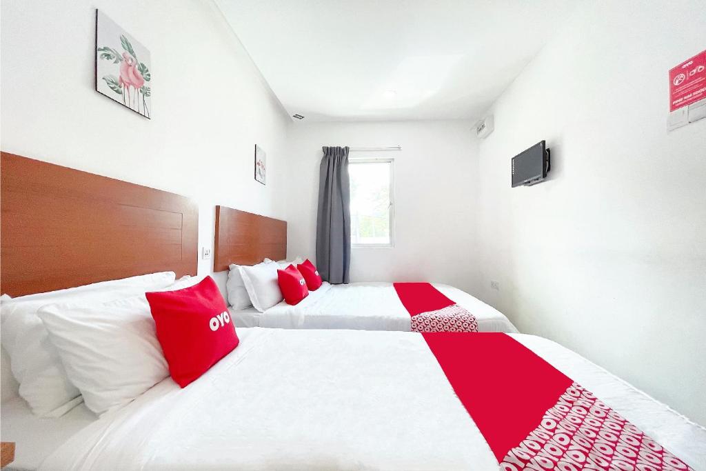 two beds in a room with red and white pillows at OYO 90334 Mawlaya Hotel in Bayan Lepas