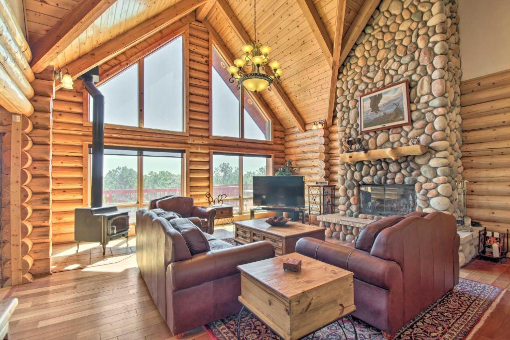 a log cabin living room with a stone wall at Hot Tub, Game Room and Theater Luxe Show Low Home in Show Low
