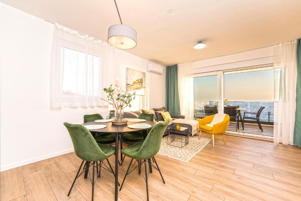 a living room with a table and green chairs at Blue waves, beachfront modern apartment in Mandre