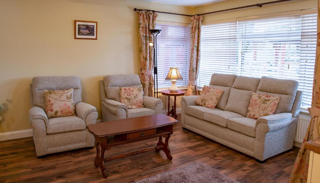 een woonkamer met 2 stoelen, een bank en een tafel bij Causeway Lodge in Bushmills