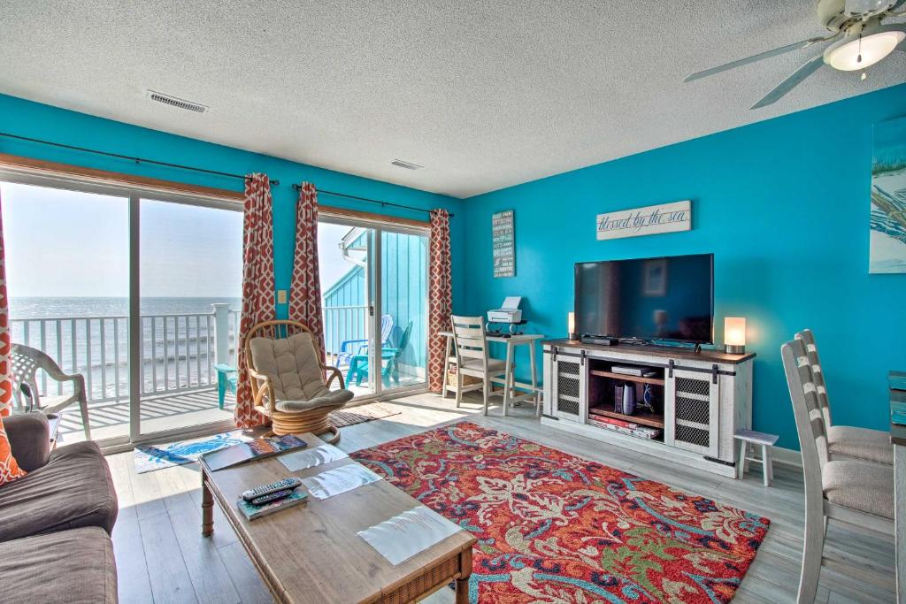 sala de estar con sofá, TV y mesa en Kure Beach Condo with Panoramic Ocean Views!, en Kure Beach