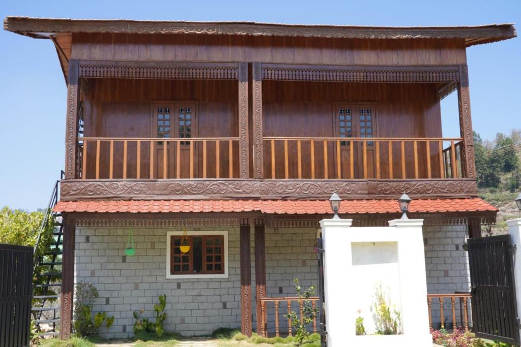 una casa con balcón en la parte superior en Kee2 Wood House en Kodaikānāl