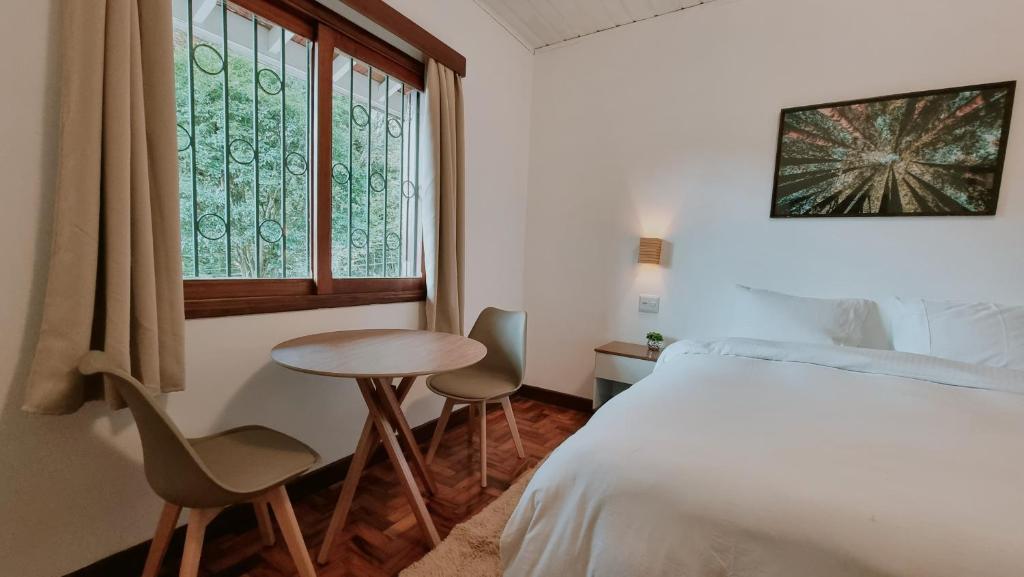 um quarto com uma cama, uma mesa e uma janela em Casa Wald em Campos do Jordão