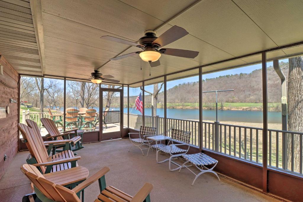 a screened in porch with chairs and a ceiling fan at Scenic Riverview Getaway with Screened Porch! in Norfork