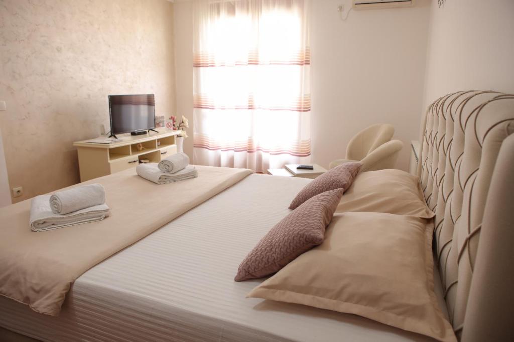 Apartman Pegasus في Vrnjačka Banja: غرفة نوم بسرير ومخدتين وتلفزيون