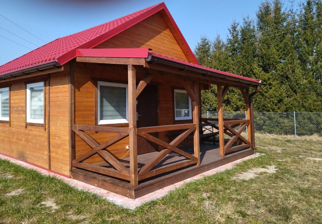 a large wooden cabin with a red roof at Domki Jastrzębia Mazury in Pasym