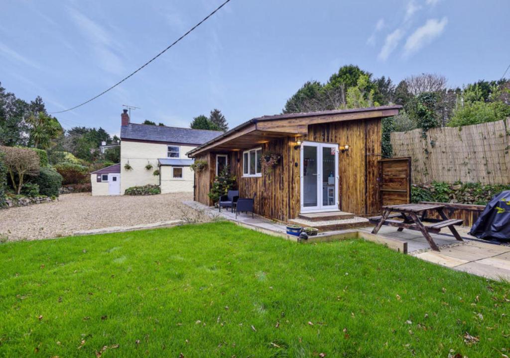 una pequeña casa con una mesa de picnic en un patio en Minimoore Lodge. Perfect for walkers, cyclists and surfers., en Scorrier