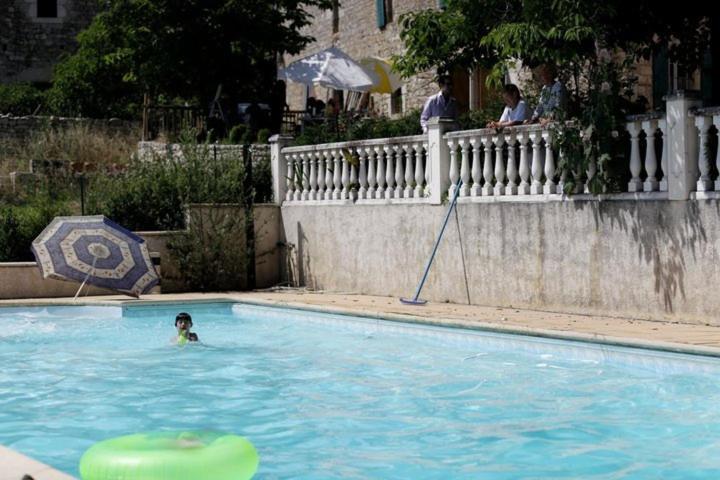 eine Person, die in einem Pool mit Sonnenschirm schwimmt in der Unterkunft Les gîtes de Franck in Fayssac