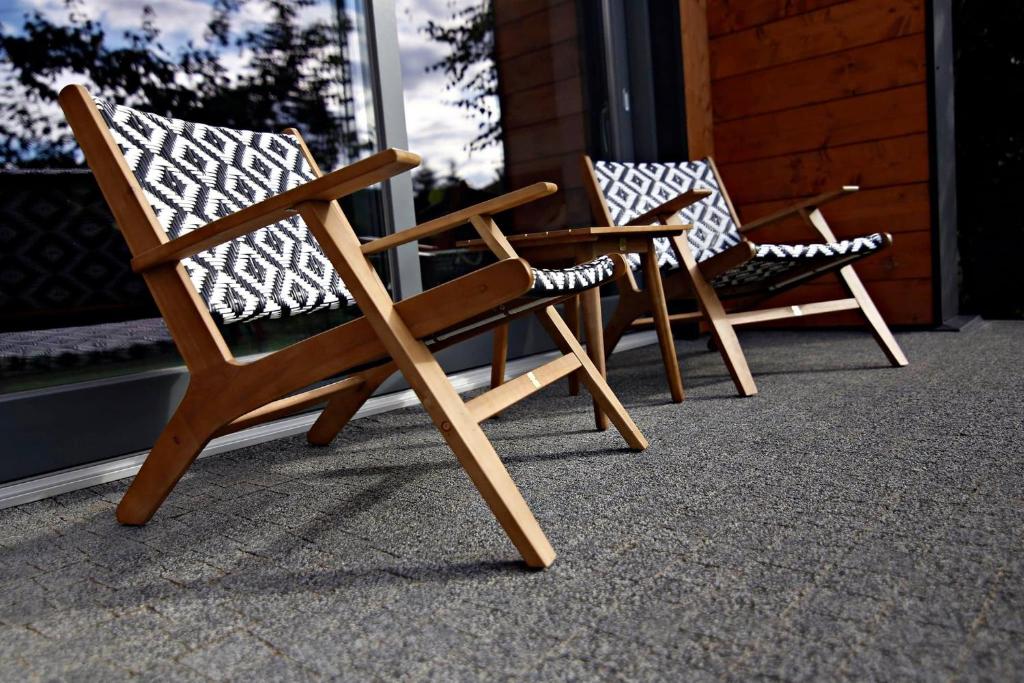- deux chaises assises sur une terrasse couverte dans l'établissement Noclegi LIW APARTMENTS Hotel Apartamenty, à Liw