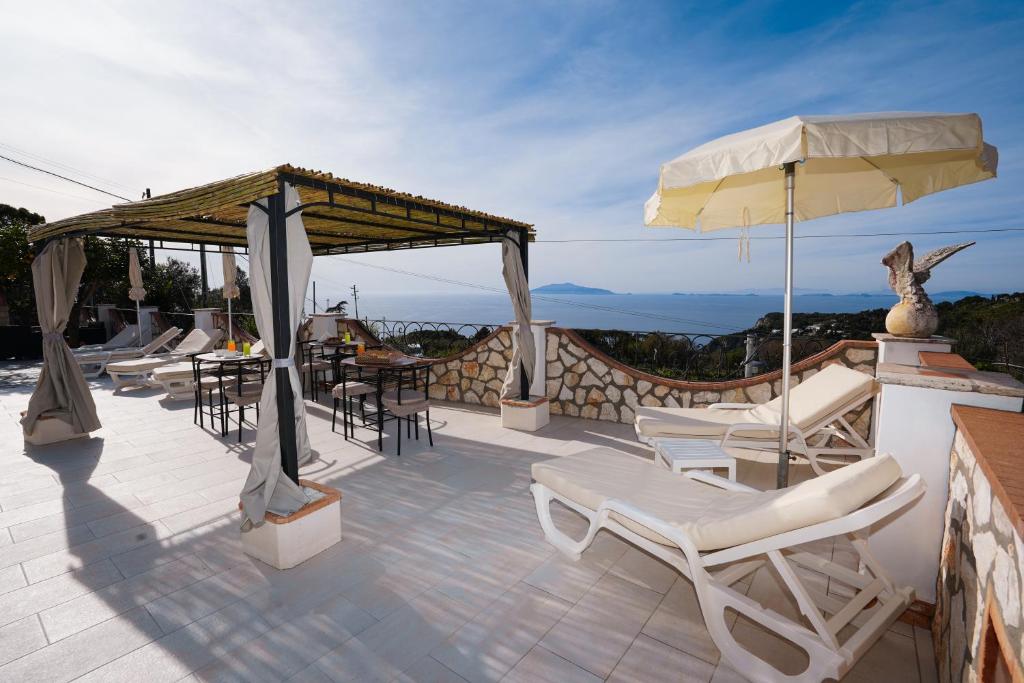 a patio with chairs and an umbrella and a table at Casa Astra in Anacapri