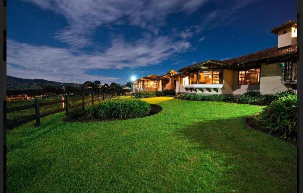 uma casa com um relvado verde em frente em Hacienda El Rejo em Machachi