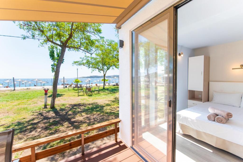 a bedroom with a bed and a balcony with a view at Vilas in the garden by the sea in Sikia