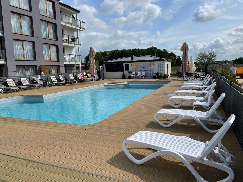 a row of lounge chairs next to a swimming pool at BalticSea Apartamenty in Sarbinowo