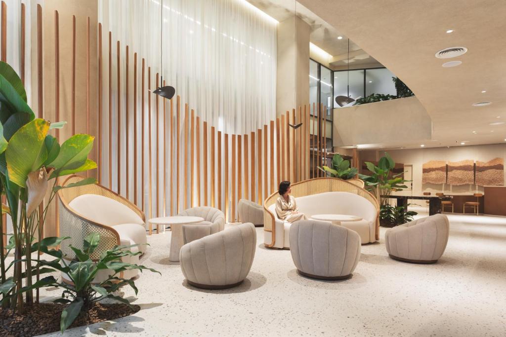 a person sitting in a lobby with chairs and tables at QOYA Hotel Curitiba, Curio Collection by Hilton in Curitiba
