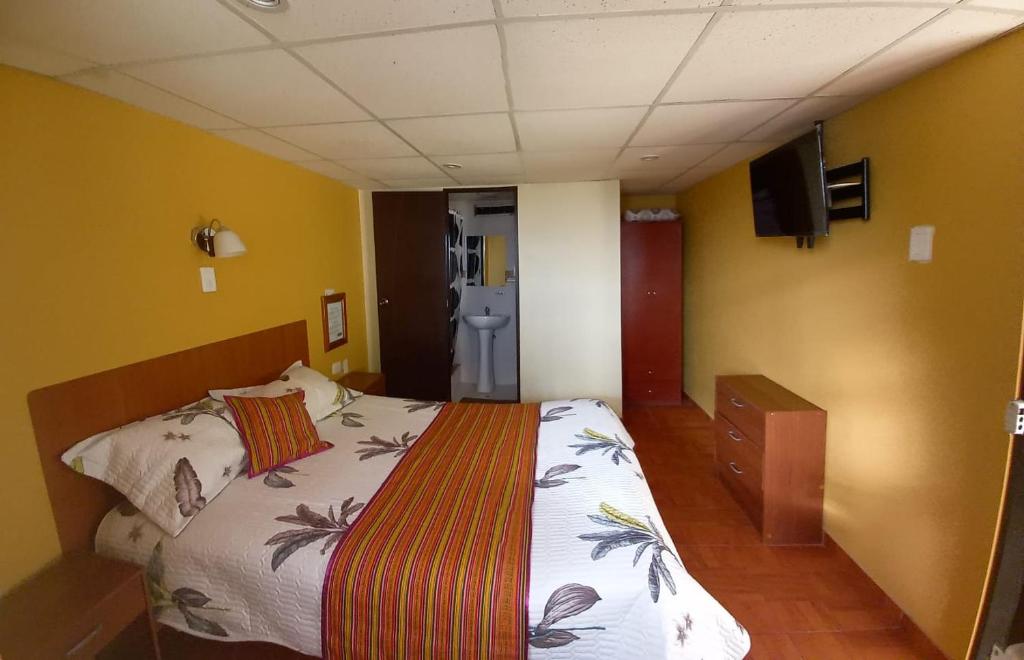 een slaapkamer met een bed in een kamer met gele muren bij Hotel Las Lomas in Huancayo