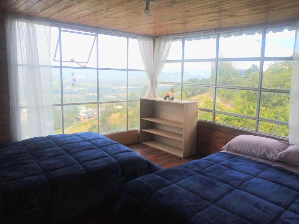 a bedroom with a bed in front of a large window at Cabaña del Colibri, la Guacamaya y la Mariposa in Sopo