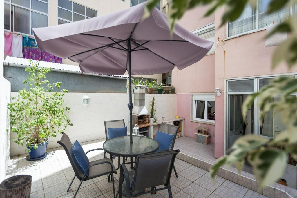 un patio con mesa, sillas y sombrilla en Be Local - Flat with 1 bedroom and terrace in Moscavide - Lisbon, en Lisboa