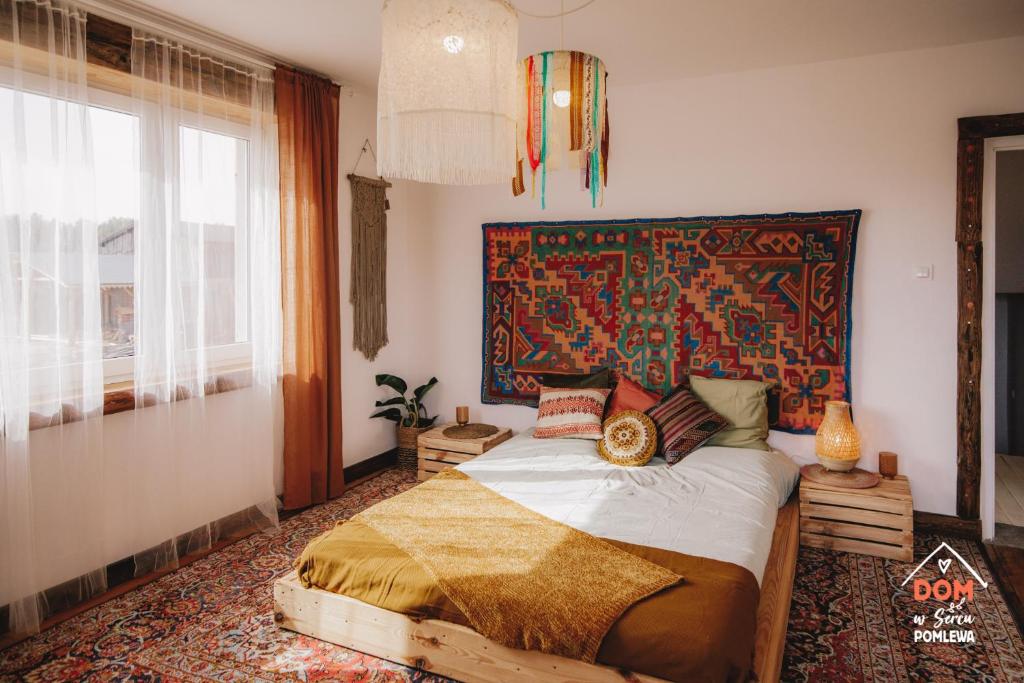a bedroom with a bed with a tapestry on the wall at Dom w sercu Pomlewa in Pomlewo